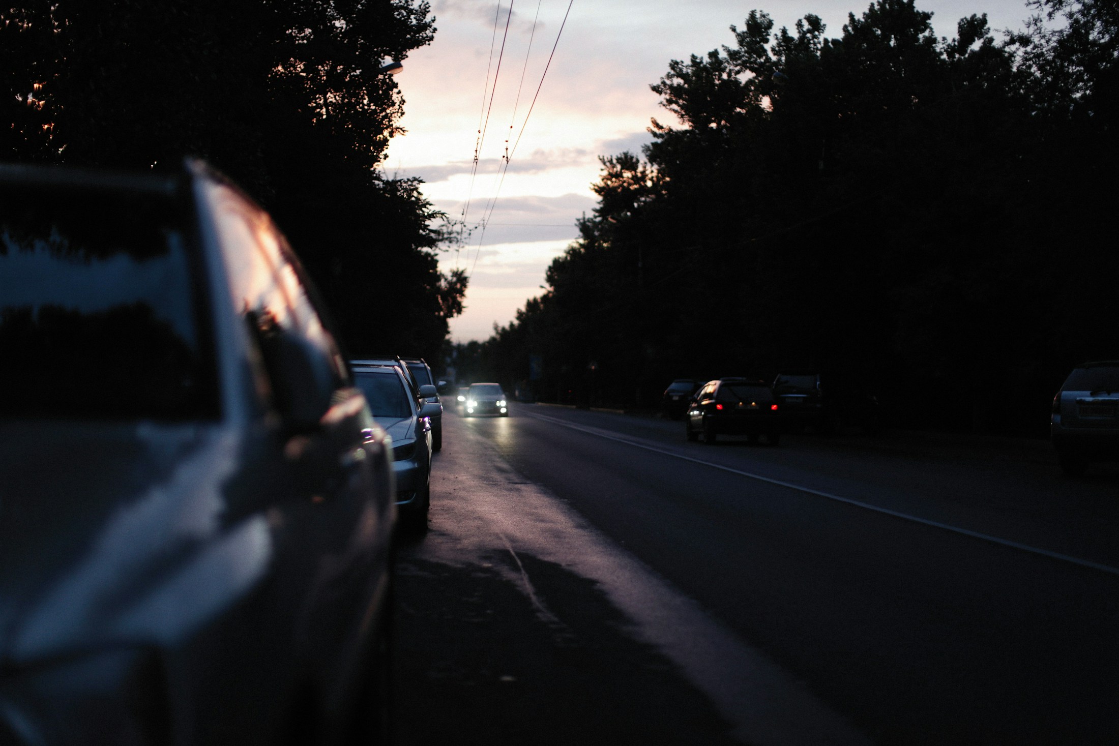Parked cars beside a wet road at quiet dusk