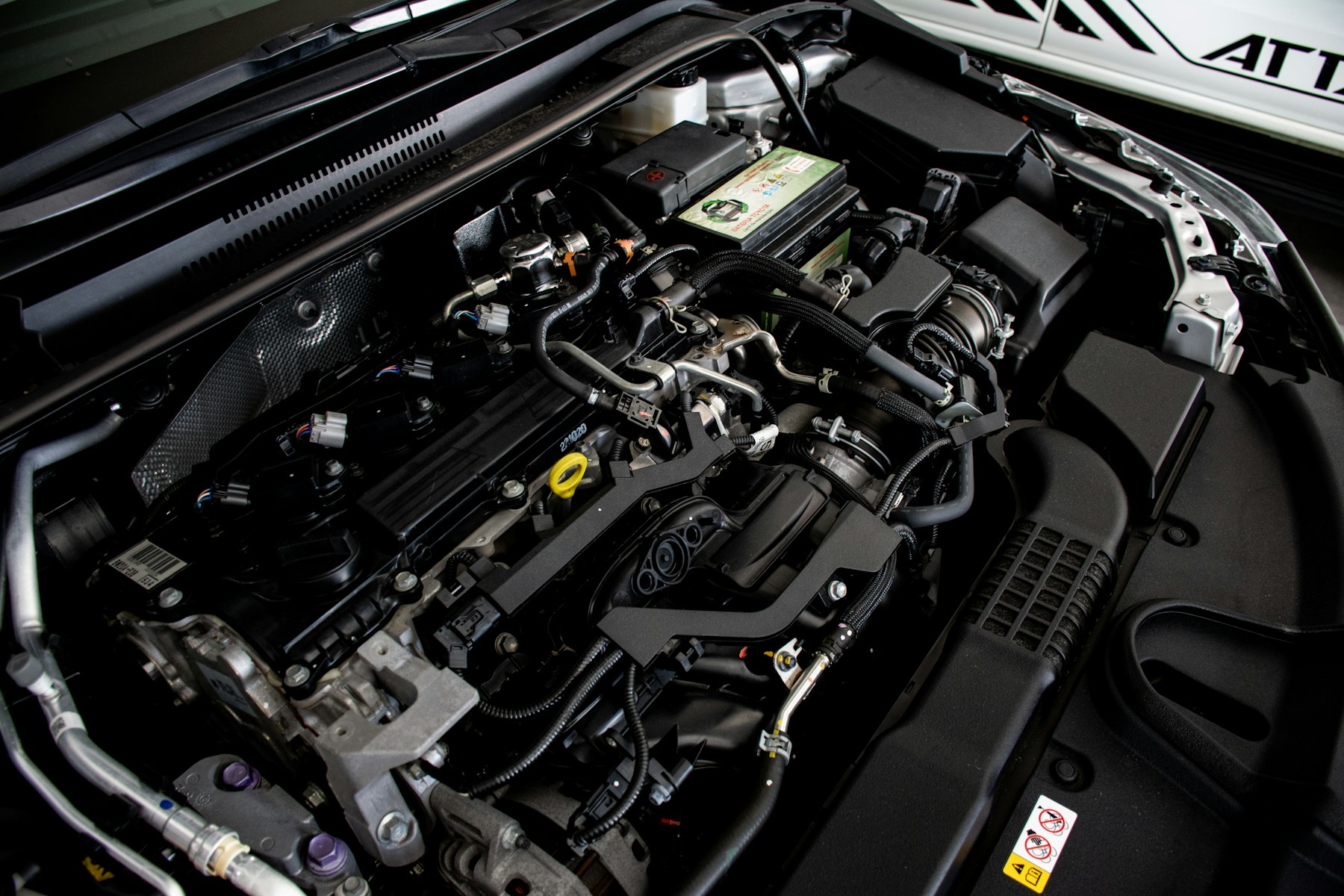 Open car hood in a clean workshop during a routine inspection