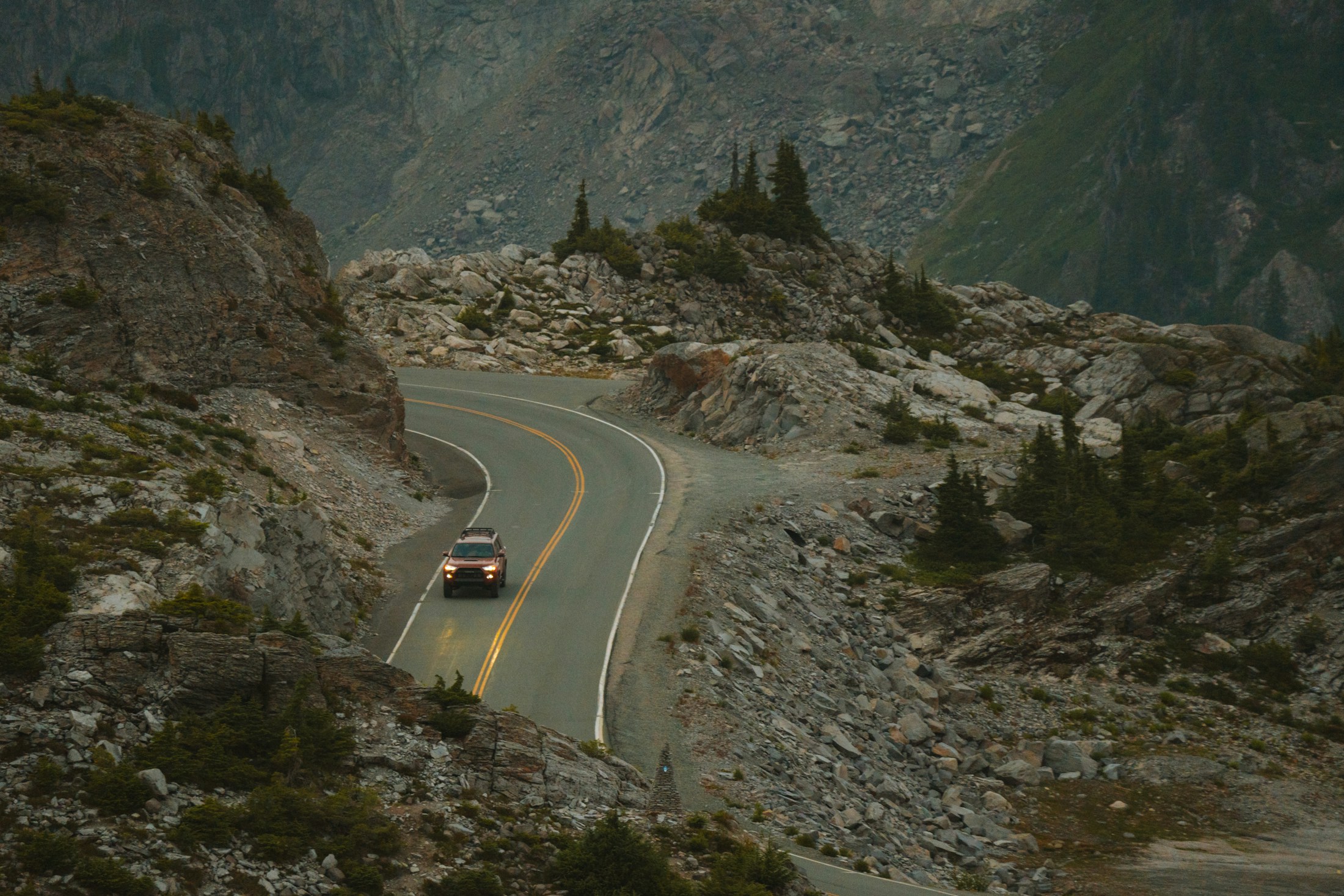 A winding road tracing a steep green mountain pass
